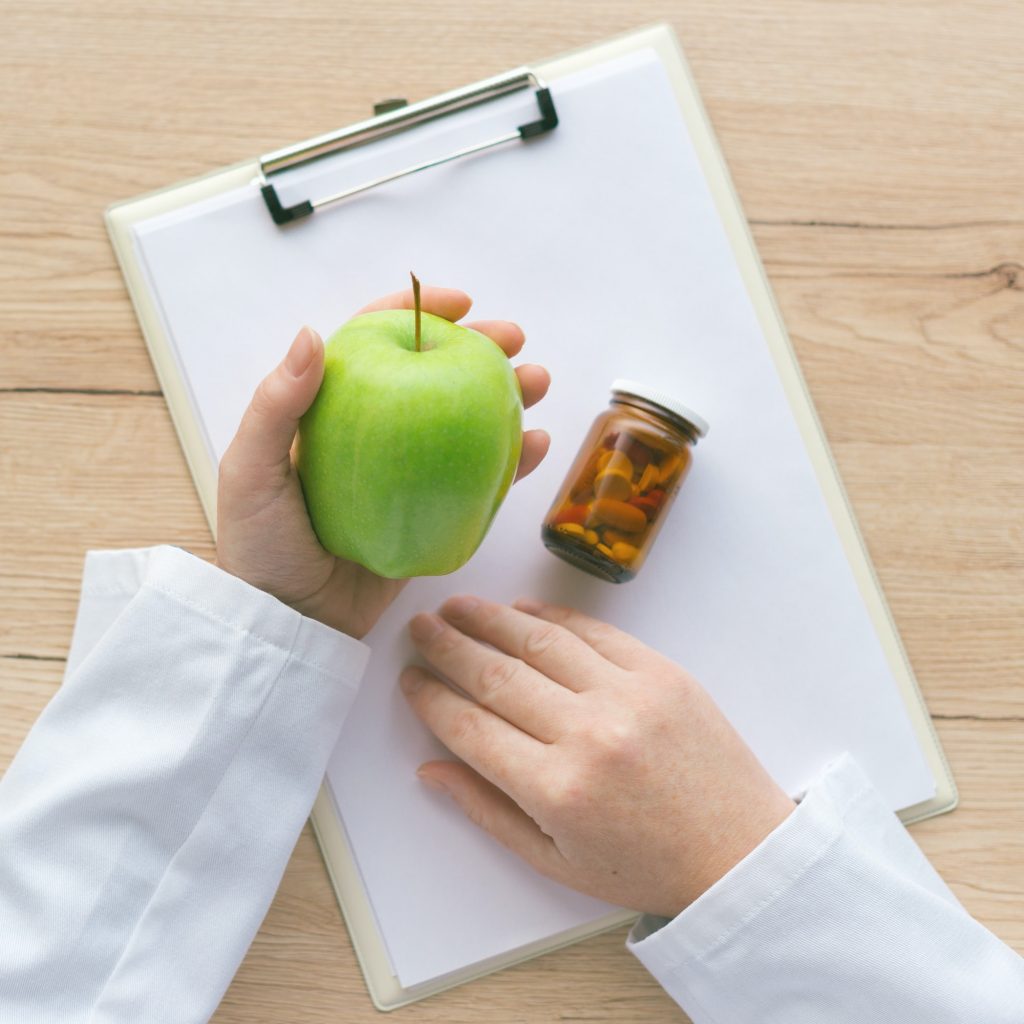 Doctor advising apple instead of pills and antibiotics